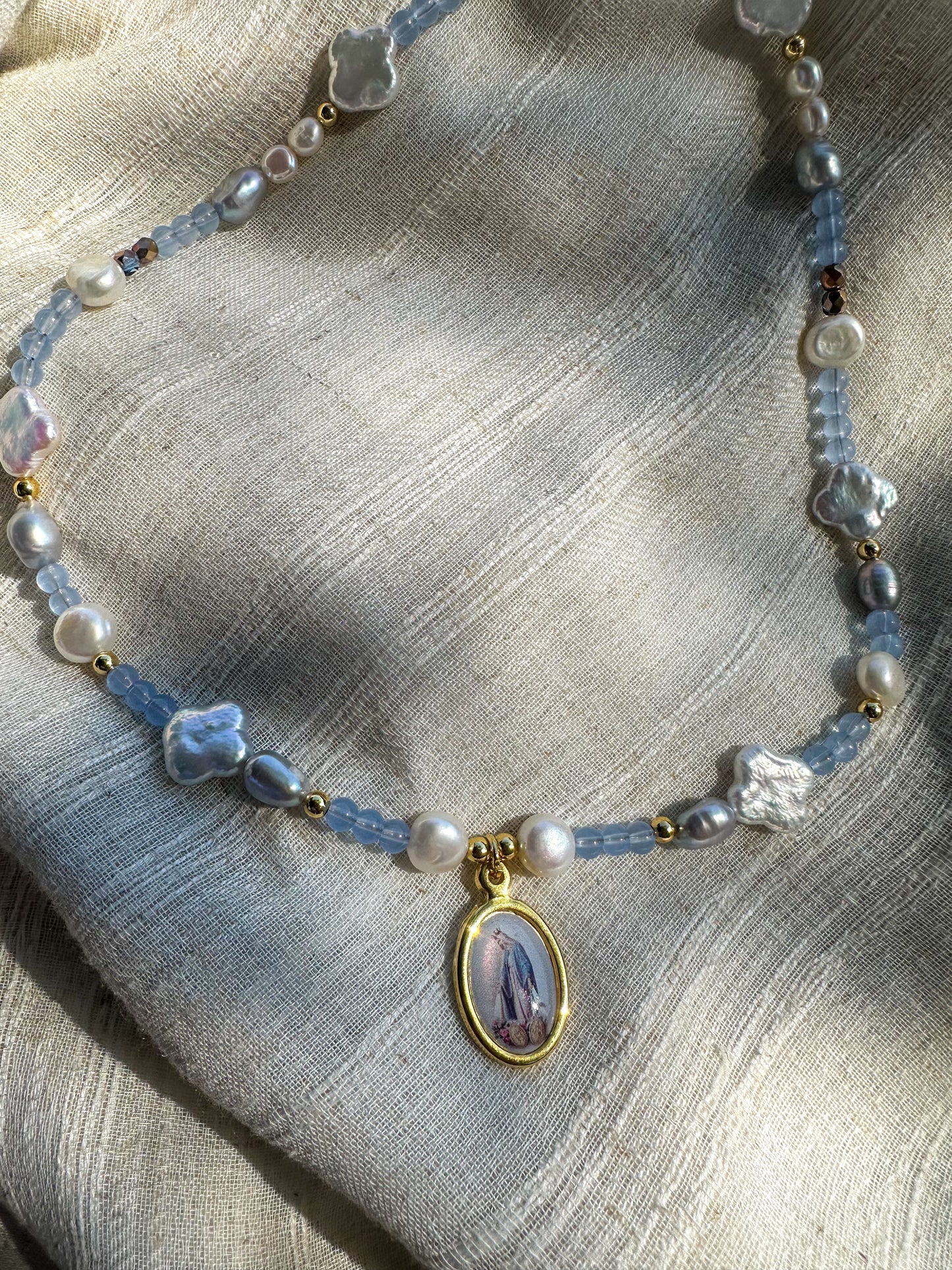 Beaded necklace featuring fresh water pearls and glass beads. Virgin Mary pendant