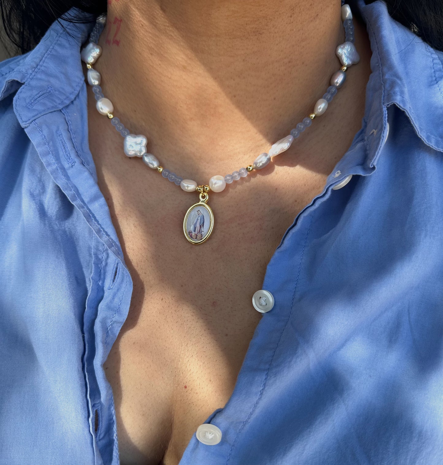 Model wearing Beaded necklace featuring fresh water pearls and glass beads. Virgin Mary pendant